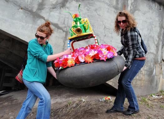 two people maneuvering an art float to the shoreline of Onondaga Creek